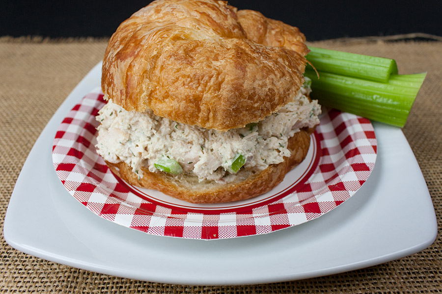 Savory Chicken Salad in a croissant on a white and red checked plate