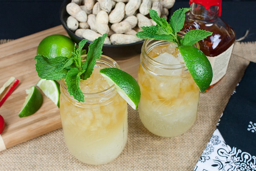 Two Kentucky Mule drinks in mason jars garnished with fresh mint and lime wedges.