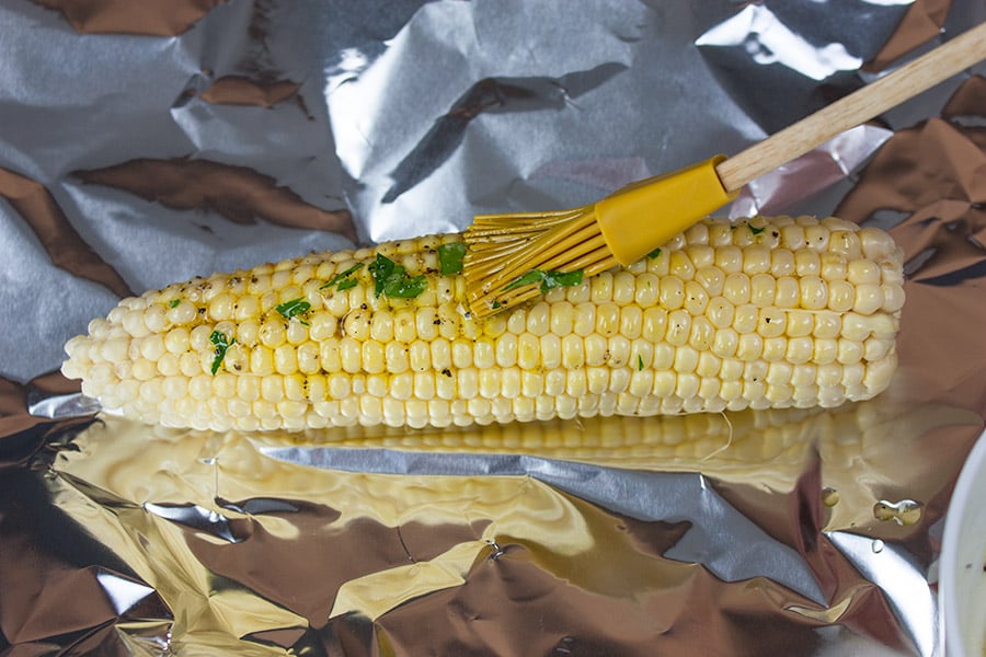 Grilled Parmesan Corn On The Cob - corn cob on a foil sheet brushed with oil mix
