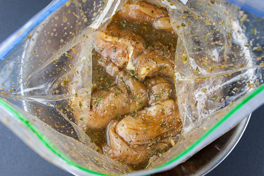 Chicken marinating in a zip top bag.