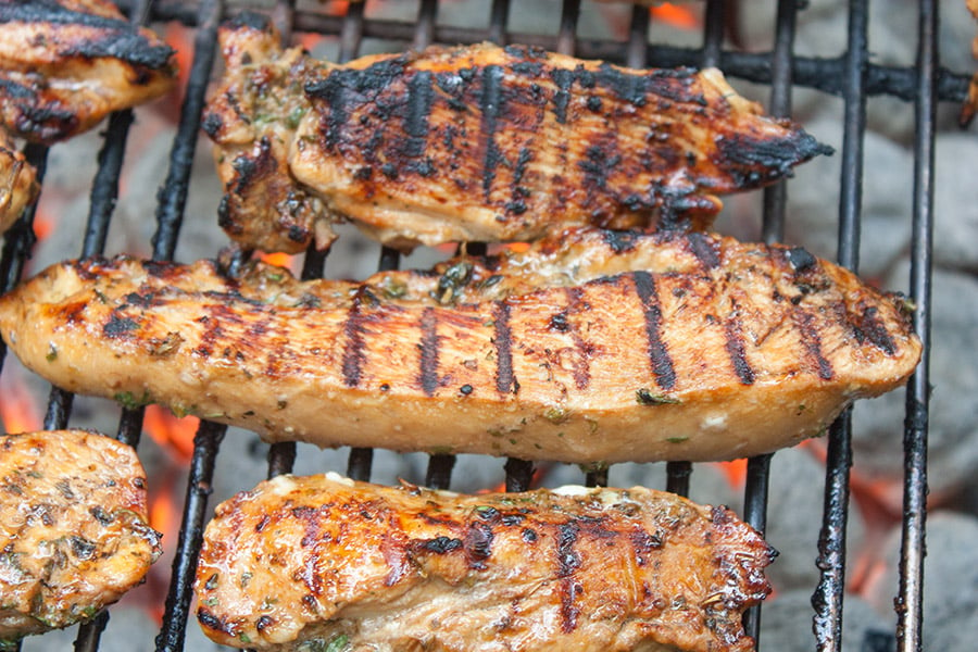 Marinated chicken pieces cooking on the grill.