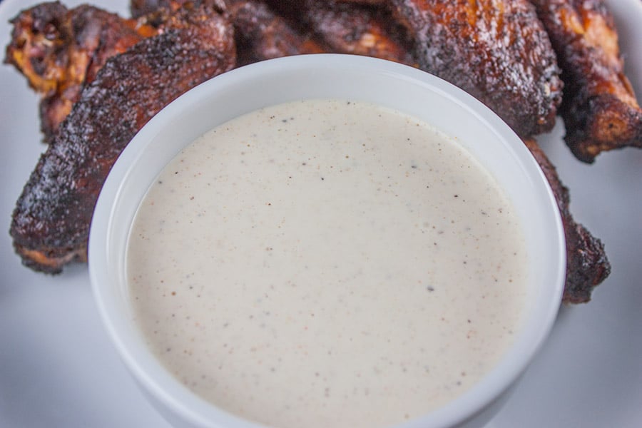 Alabama White BBQ Sauce in white ramekin surrounded by smoked chicken wings.