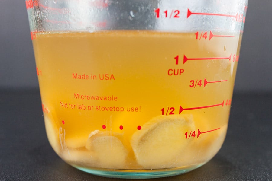 boiled lemon juice and ginger slices in glass measuring cup