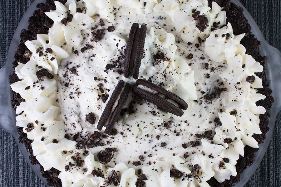 No Bake Cookies and Cream Pie garnished with whipped cream stars and crushed oreo cookies