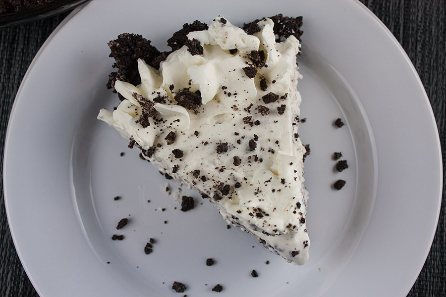 slice of Cookies and Cream Pie on white plate cookie crumbles scattered on plate