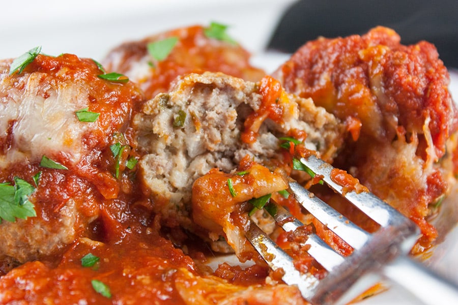 close up of Baked Parmesan Meatballs one cut open on a fork