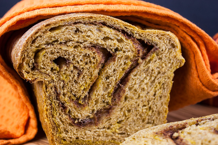 Pumpkin cinnamon swirl bread loaf sliced and draped in an orange towel.