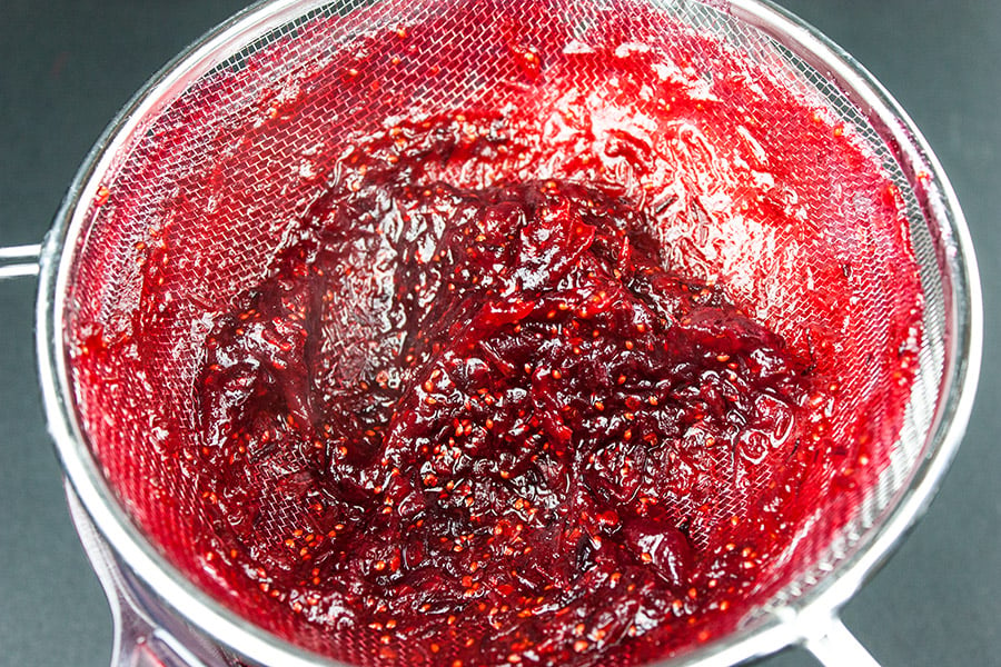 cranberry sauce being pushed through a strainer