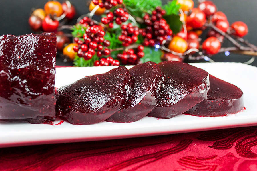 Unmolded cranberry sauce shaped like a jar and sliced in serving slices on a white platter.