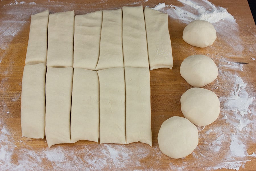 Dough sliced into pieces with 4 of them rolled into balls.