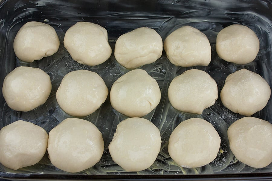 one hour dinner roll dough balls placed in a butter baking dish
