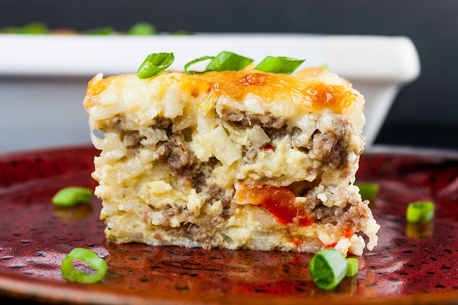 sausage hash brown breakfast casserole serving slice on red pottery plate