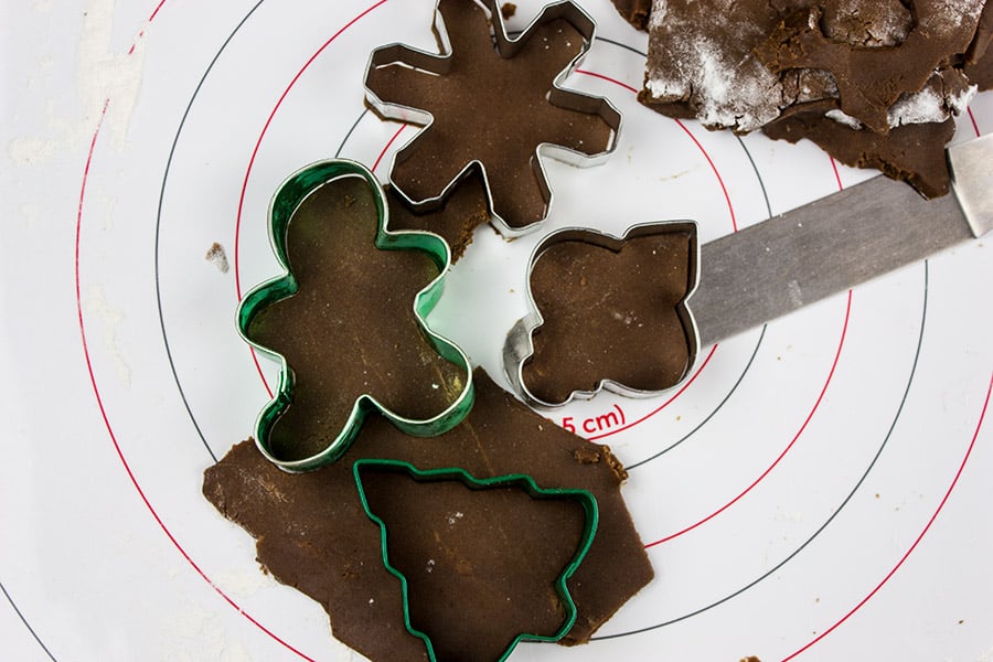 gingerbread dough cut into star gingerbread man Christmas tree and ornament on pastry mat
