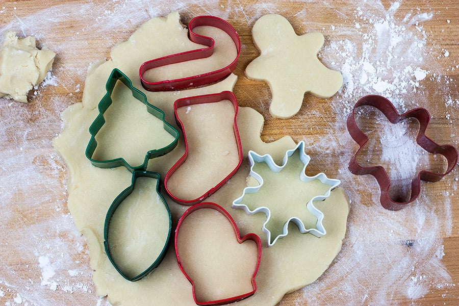 Sugar cookie dough cut out with cookie cutters placed on dough.