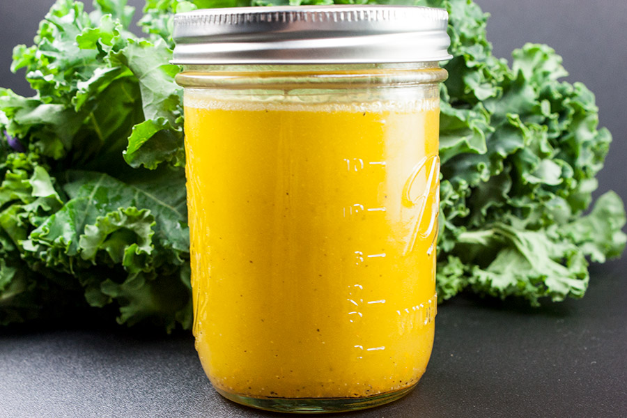 Kale and Bean Salad - citrus vinaigrette for the kale and bean salad in a mason jar with fresh bunch of kale in background