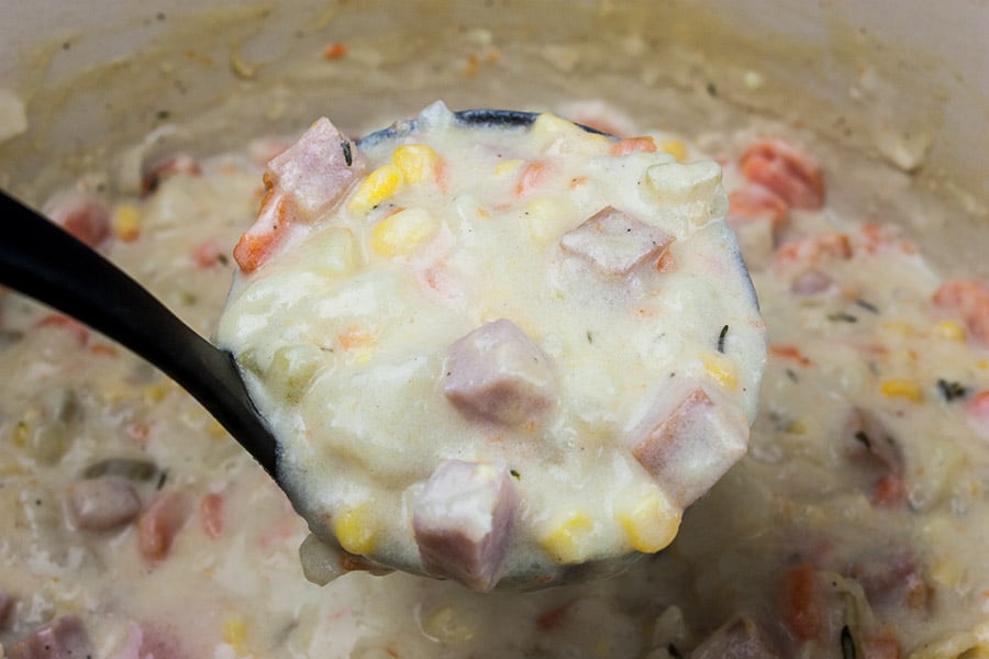 Ham and potato soup ladled out of the pot with a ladle.