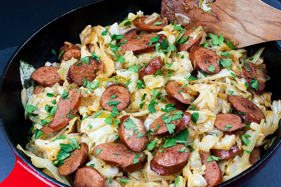 fried cabbage and sausage in red cast iron skillet