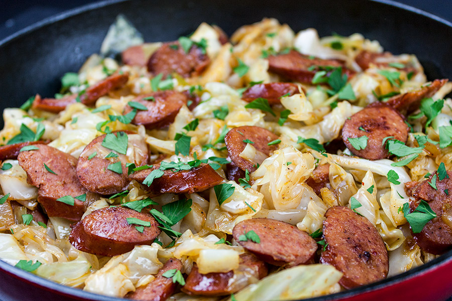 fried cabbage and sausage in red cast iron skillet