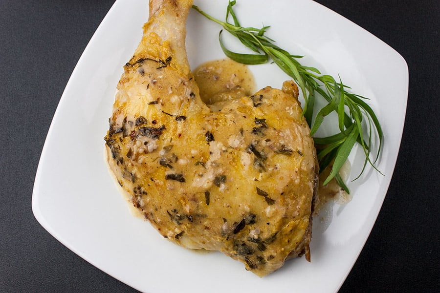 Roasted Chicken with Dijon Cream Sauce on a plate garnished with fresh tarragon.