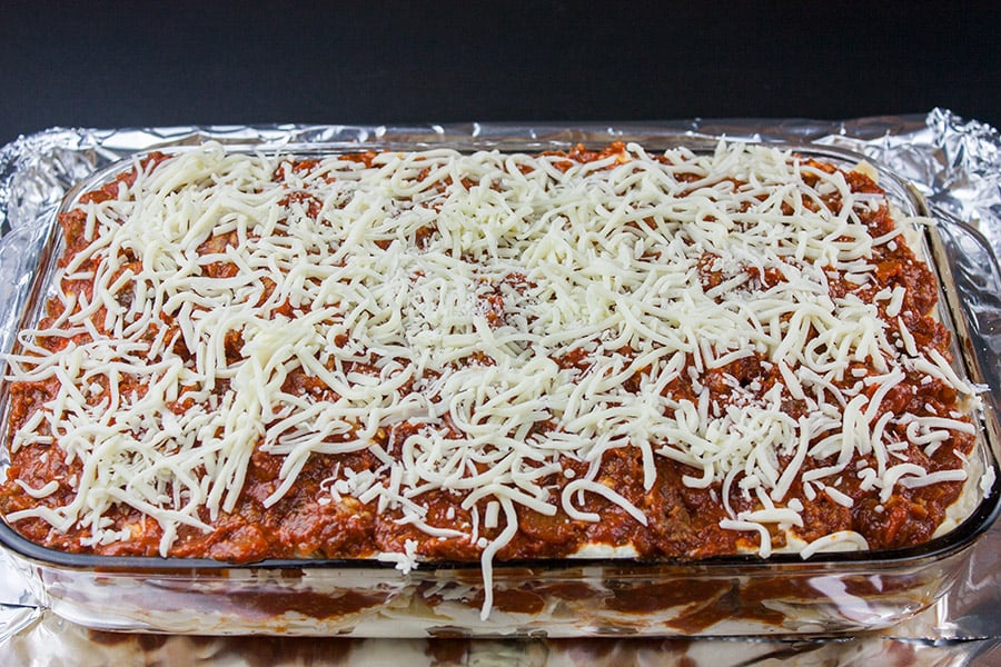 Absolute Best Ever Lasagna - uncooked lasagna in a baking pan on top of a foil lined baking sheet