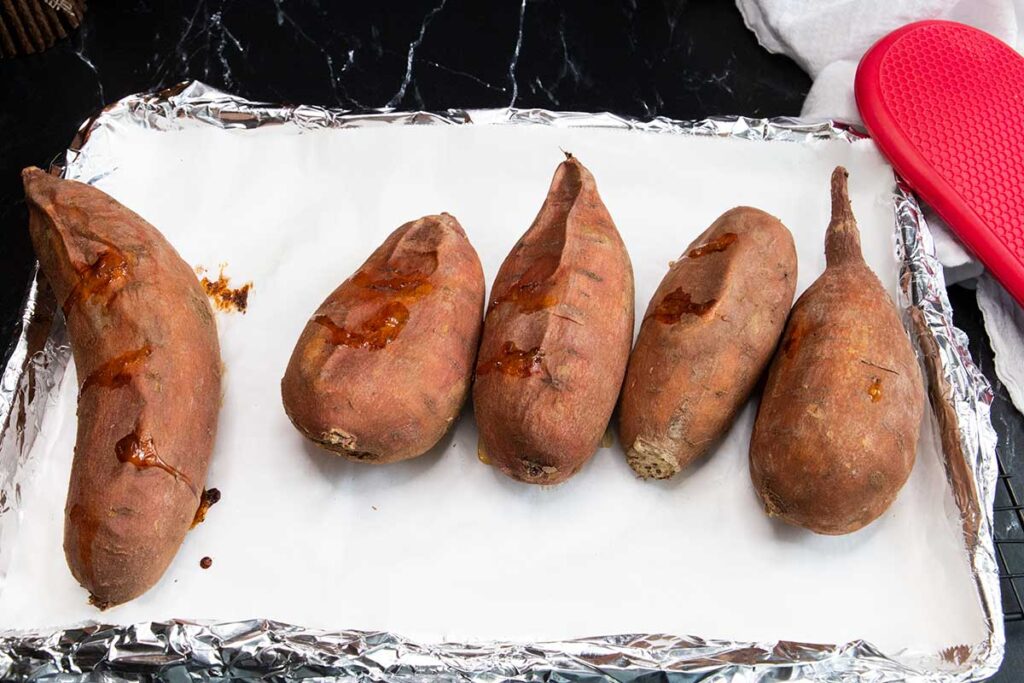 Baked sweet potatoes on baking sheet.