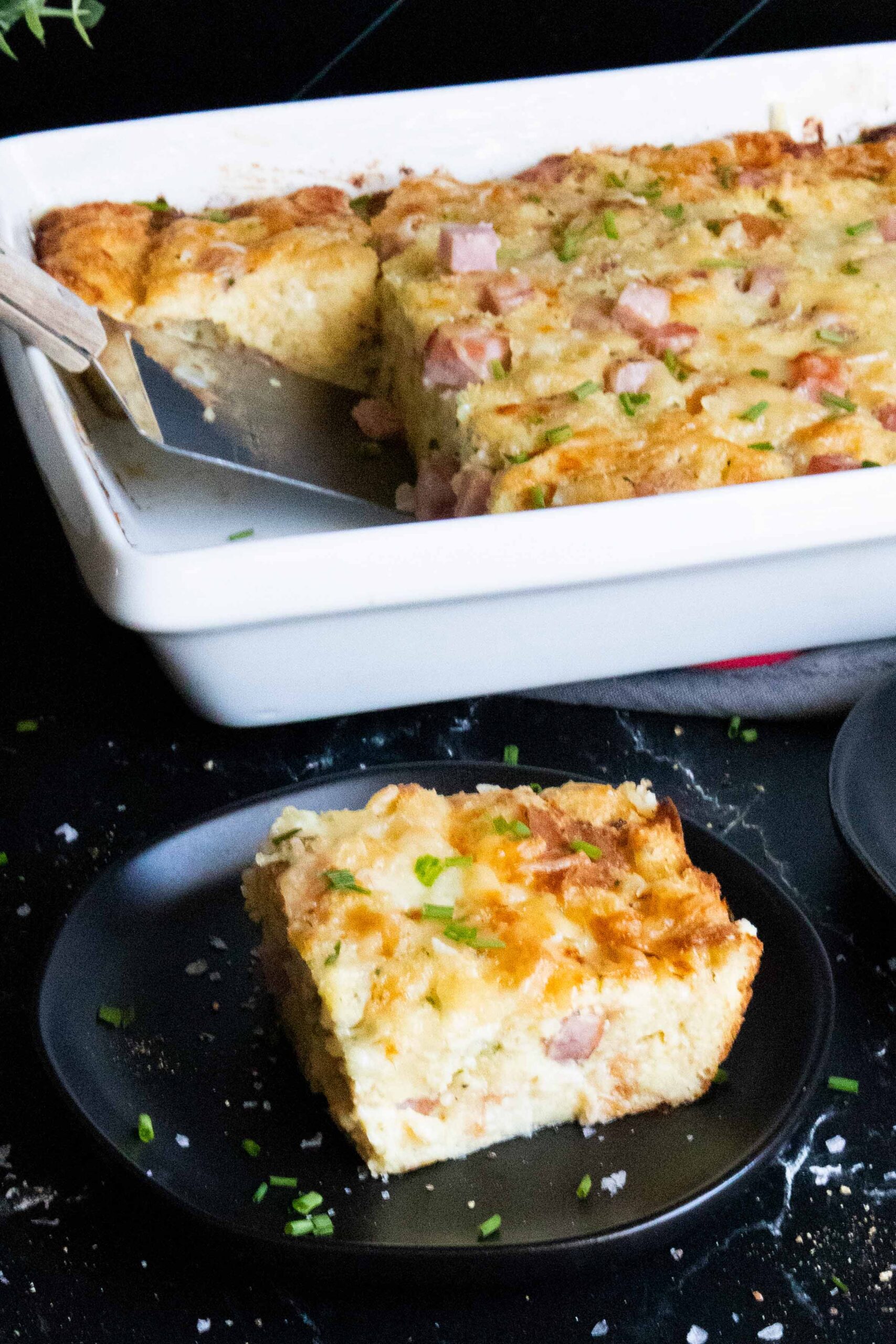 Serving of ham and cheese strata on a dark plate.