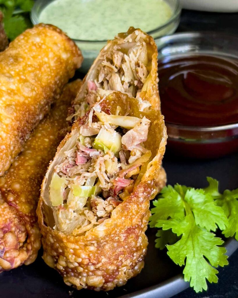 Redneck egg rolls on a dark plate with dipping sauces.