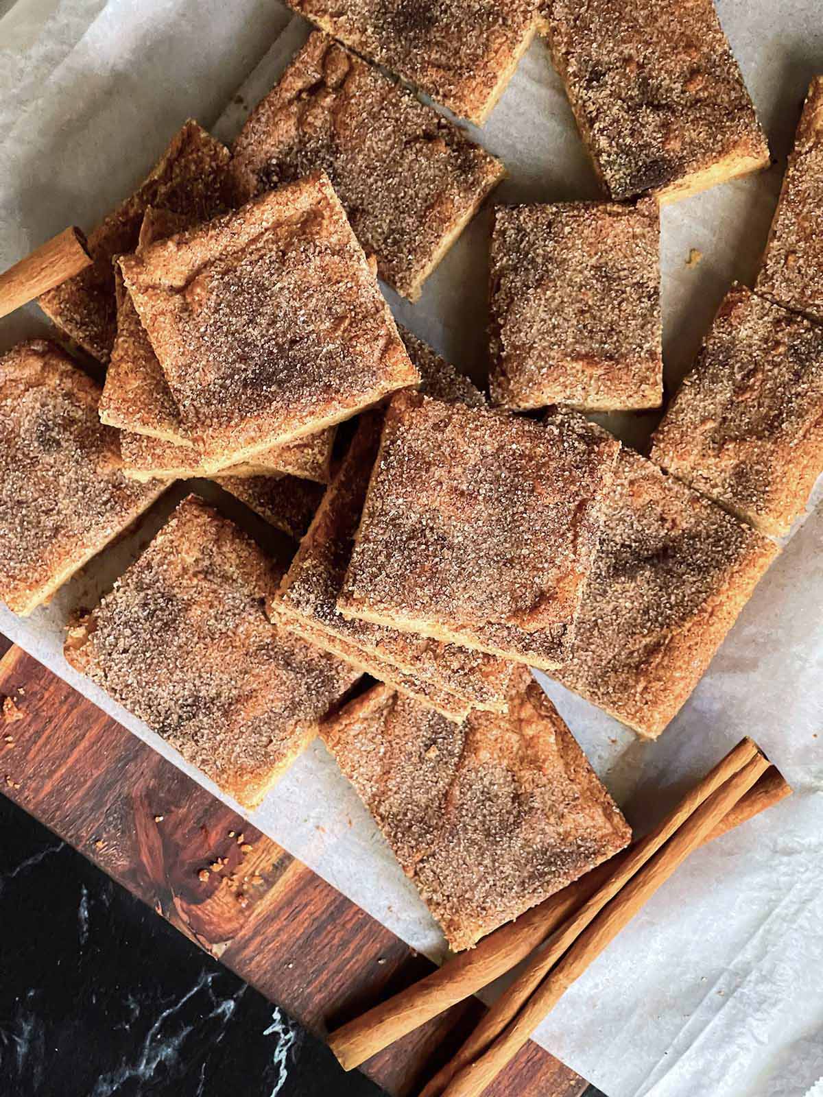 Snickerdoodle bars stacked on a parchment paper lined wooden board,