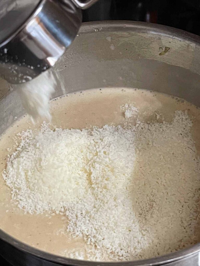 Adding parmesan to the tetrazzini mixture.