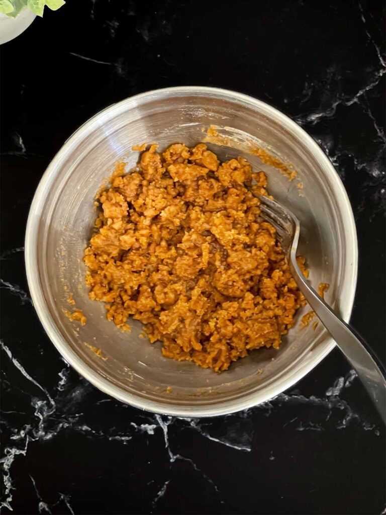 Streusel topping ingredients for carrot coffee cake mixed in a metal bowl on a dark surface.