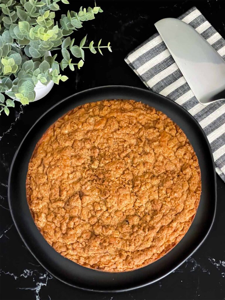 Baked carrot coffee cake on a dark platter on a dark surface.