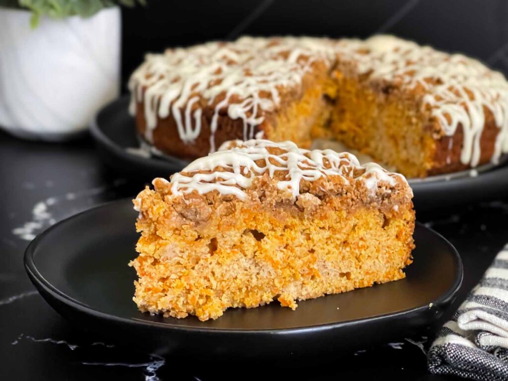 Carrot coffee cake slice on a dark plate on a dark surface.