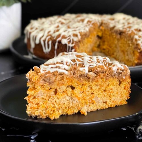 Carrot coffee cake slice on a dark plate on a dark surface.