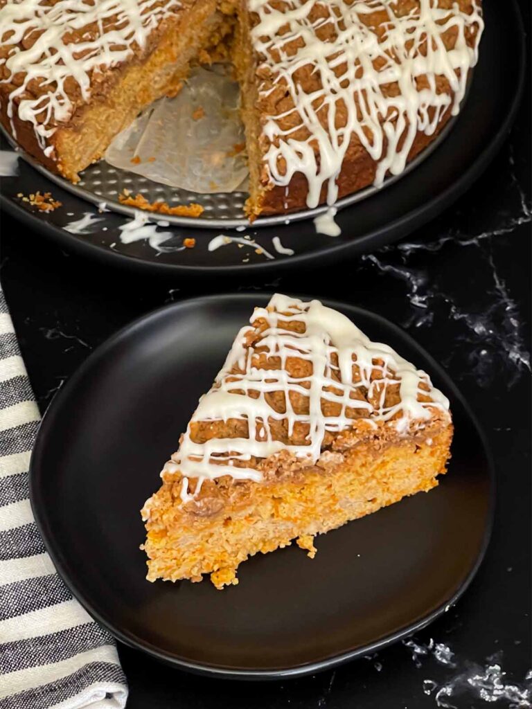 Carrot coffee cake slice on a dark plate on a dark surface.