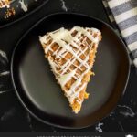 Slice of carrot coffee cake on a dark plate.