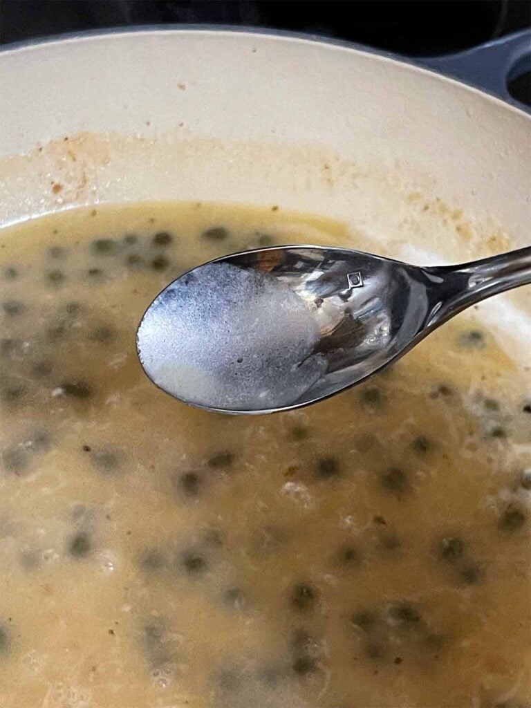 Piccata sauce cooking in a skillet.