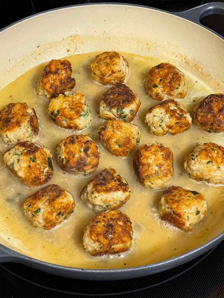 Chicken Piccata Meatballs cooking in a skillet.