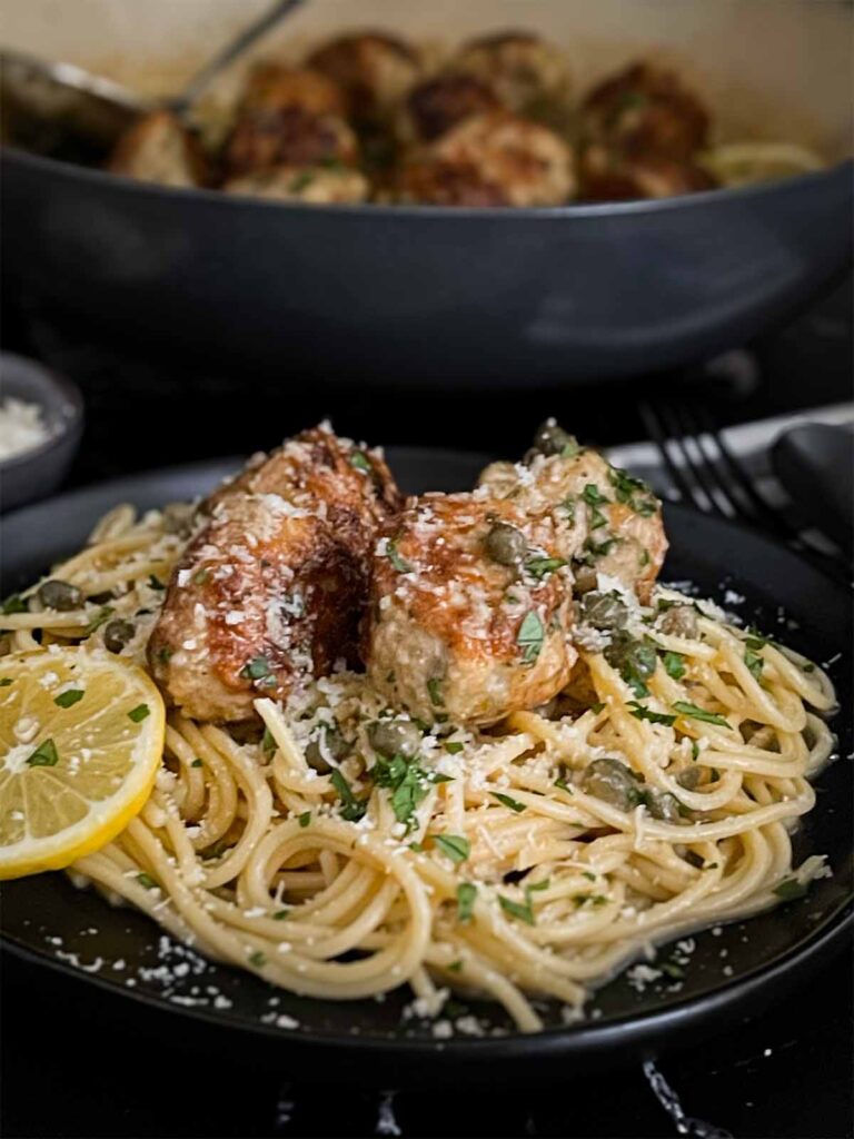 Chicken Piccata Meatballs on a bed of pasta.