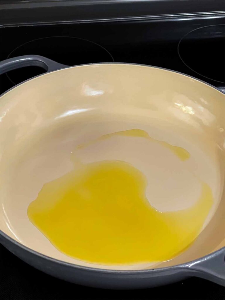 Olive oil heating in a skillet.