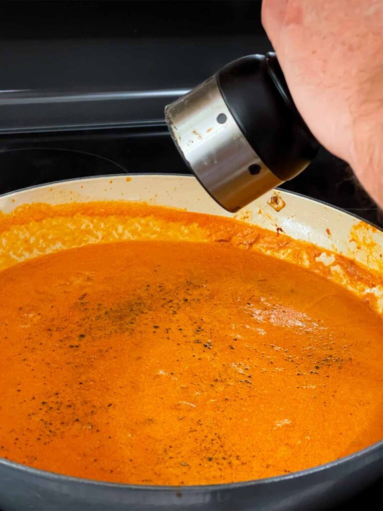 Seasoning Vodka sauce cooking in a skillet.