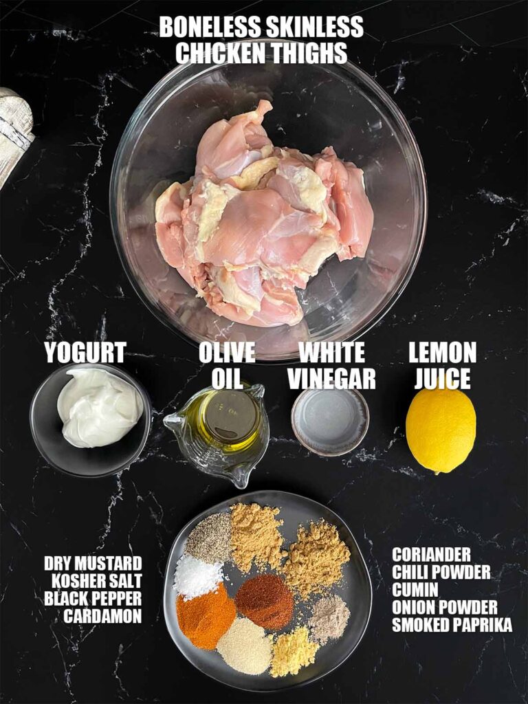 Ingredients needed to make chicken shawarma on a dark plate.