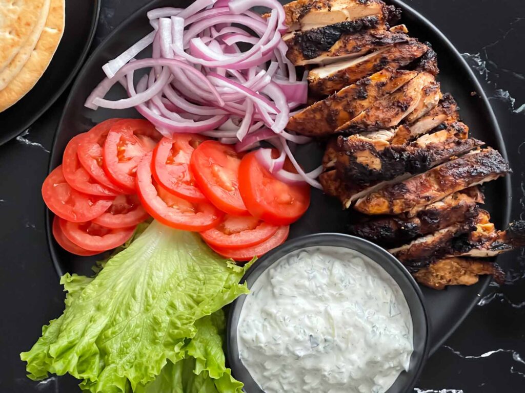 Grilled chicken shawarma on a dark plate.