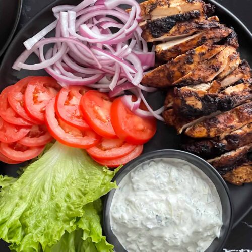 Grilled chicken shawarma on a dark plate.