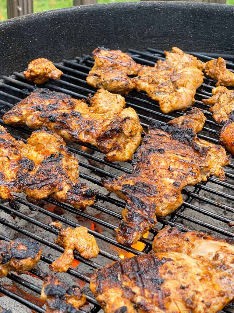 Chicken thighs cooking on a kettle grill.