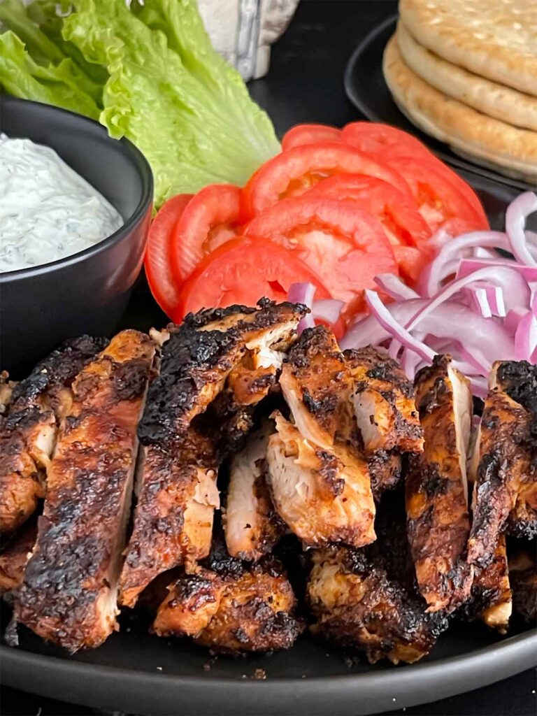 Grilled chicken shawarma on a dark plate.