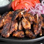 Grilled chicken shawarma on a dark plate.