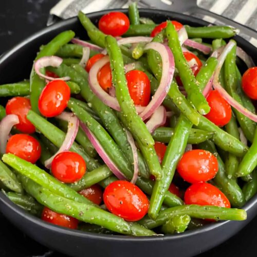 Italian green bean salad in a dark bowl on a dark surface.