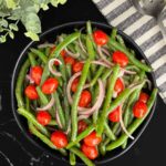 Italian green bean salad in a dark bowl on a dark surface.