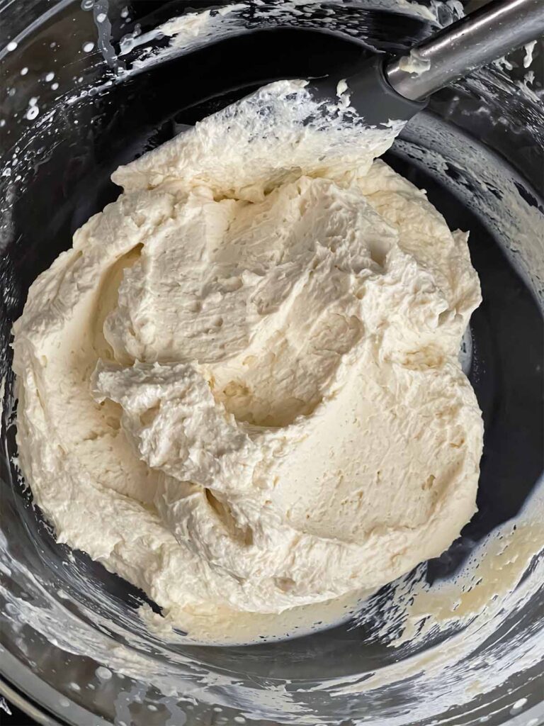 Ricotta mixture folded into the whipped cream in a glass mixing bowl.