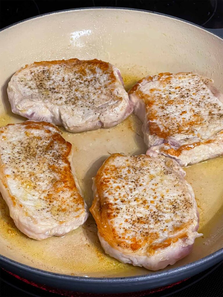 Browned pork chops in a skillet.